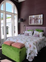 Лиловая спальня в сочетании с зеленым пуфиком и подушками